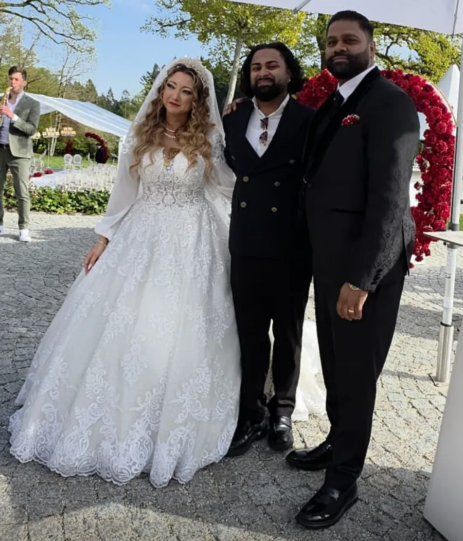 DJ $AARU mit Brautpaar vor einem Rosenbogen